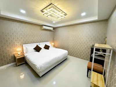 a bedroom with a large white bed and a chandelier at Huai Khwang Townhome in Ban Na Song