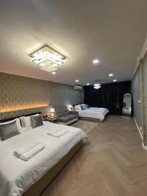 a hotel room with two beds and a couch at Huai Khwang Townhome in Ban Na Song