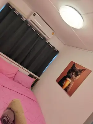 a bedroom with a pink bed and a picture of a cat at อิมแพ็ค คอนโดเมืองทอง in Thung Si Kan