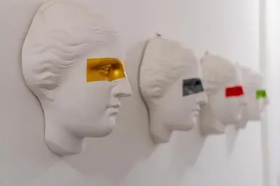 a row of white heads hanging on a wall at Studio Kunst in Bangkok