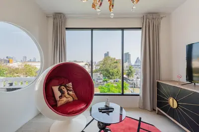 a living room with a red chair and a large window at Studio Kunst in Bangkok