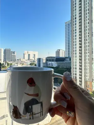 a person holding a coffee cup with a picture of a man at 2 Bed 2 Bath Condo Steps to BTS&MRT in Bangkok