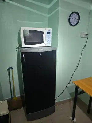 a microwave on top of a refrigerator next to a clock at 103 Lovely AC apartment with private kitchen in Bangkok