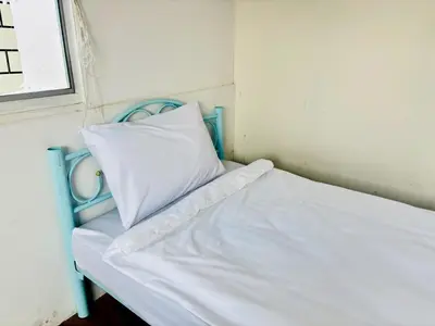 a white bed with a blue frame and a pillow at BKK Rama3 Guest House in Bangkok
