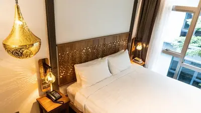 a bedroom with a large white bed with a window at Tints of Blue Hotel in Bangkok