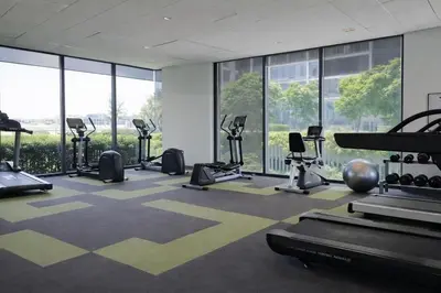 a gym with treadmills and elliptical machines and windows at Cozy Japandi Stay on Sukhumvit in Bangkok
