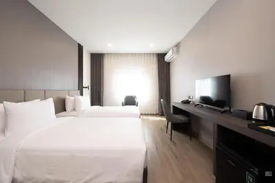 a hotel room with two beds and a desk with a television at SureStay Plus by Best Western Ramkhamhaeng Airport Rail Link Bangkok in Bangkok