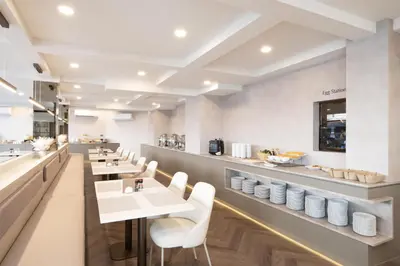 a restaurant with white tables and white chairs at SureStay Plus by Best Western Ramkhamhaeng Airport Rail Link Bangkok in Bangkok