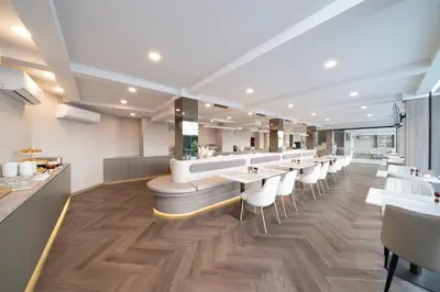 a restaurant with a long bar with white tables and chairs at SureStay Plus by Best Western Ramkhamhaeng Airport Rail Link Bangkok in Bangkok