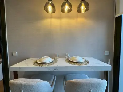 a white table with chairs and plates and lights at ห้องพักใจกลางกรุงเทพฯ ใกล้สยาม in Pratunam