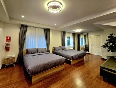 a bedroom with two beds and a large window at The Atlas hostel Bangkok in Thung Si Kan