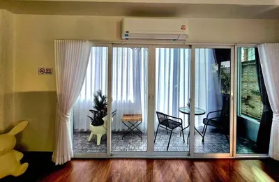 a living room with a large sliding glass door at The Atlas hostel Bangkok in Thung Si Kan