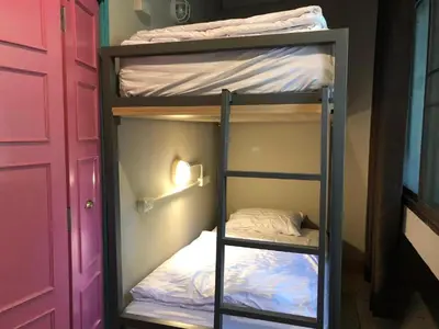 two bunk beds in a room with a door at Merge Hostel in Samphanthawong