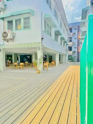 a large building with a wooden deck with tables and chairs at Easy Monday Capsule Bed and Traditional Thai Bath in Bangkok