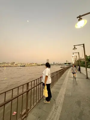 a woman standing on a pier looking at the water at Muzachi home stay and canal in Bangkok Yai