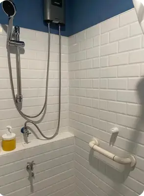 a shower in a bathroom with white tiles at mug & bed in Bangkok