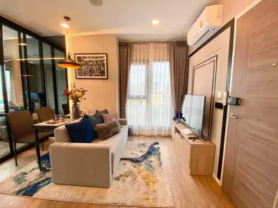 a living room with a couch and a television at New Luxury Condo 5 Min Onnut BTS - Modiz Sukhumvit 50 in Bangkok
