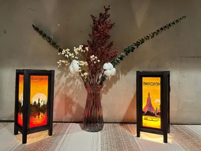 a vase with flowers in it sitting between two candles at Lesbase Women Hostel in Bangkok