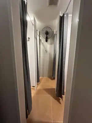 a hallway leading to a shower with a fan at Lesbase Women Hostel in Bangkok
