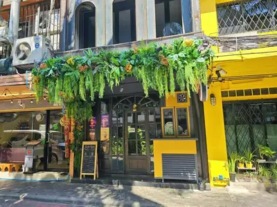 a yellow building with plants hanging from it at Lesbase Women Hostel in Bangkok