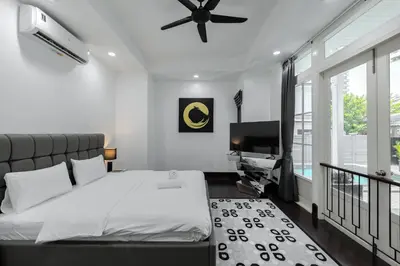 a bedroom with a bed with a ceiling fan and a desk at Thong Lo Modern Pool Villa In Center Of Bangkok in Bangkok
