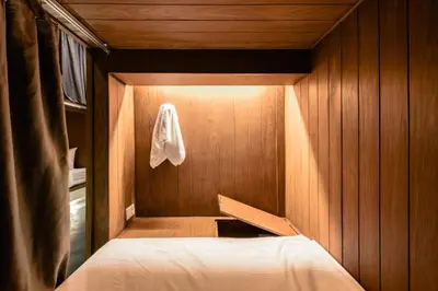 a small room with a bed in a wooden room at Once Again Hostel in Bangkok