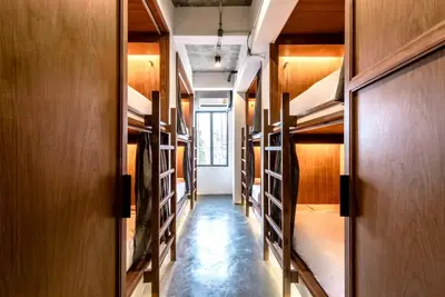 a hallway of a room with many racks ofunks at Once Again Hostel in Bangkok