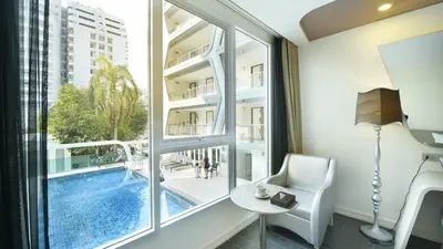 a hotel room with a view of a pool and a table and chair at Le Tada Parkview Hotel in Bangkok