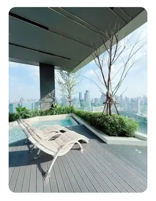 a white lounge chair sitting on a deck next to a pool at Luxury 1 Bedroom l BTS 2 mins l Pool and Gym in Pratunam