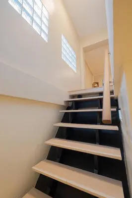 a staircase in a house with black floors and windows at Warm & Cozy Family Home, Near BTS Punnawithi in Phra Khanong