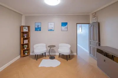 a living room with two white chairs and a table at Warm & Cozy Family Home, Near BTS Punnawithi in Phra Khanong