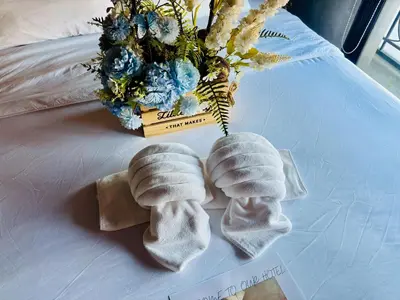 two pairs of socks on a bed with a vase of flowers at Bangkok Phattanakan32 guest house in Bangkok