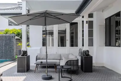 a patio with a couch and an umbrella at Thong Lo Sumptuous Double Pool Villa in Bangkok