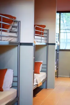 a room with bunk beds with orange pillows at Nitra Hostel Siriraj in Bangkok