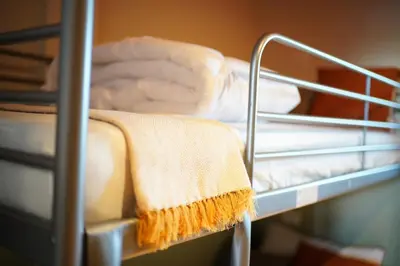 a metal bunk bed with a towel on it at Nitra Hostel Siriraj in Bangkok