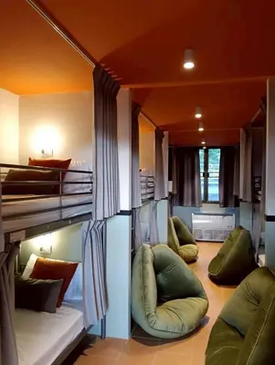 a room with three bunk beds and two chairs at Nitra Hostel Siriraj in Bangkok