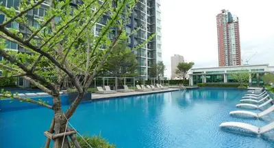 a large swimming pool with white chairs and a tree at Supreme Spacious 2-Bedroom in Prime Location! BTS Thonglor in Bangkok
