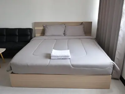 a large bed in a room with a black couch at Hi Impact Muangthong T9 in Nonthaburi
