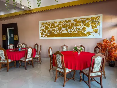 a dining room with red tables and chairs and a painting at POR SAHA Hotel Ramkhamhaeng 100 in Bang Kapi