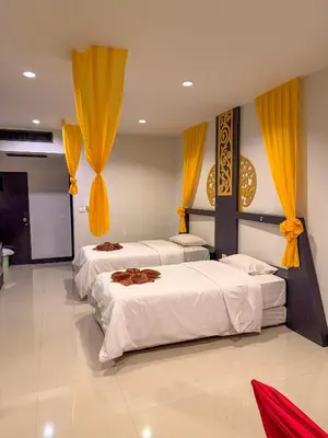 two beds in a room with yellow curtains at POR SAHA Hotel Ramkhamhaeng 100 in Bang Kapi