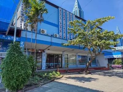 a blue building with a tree in front of it at POR SAHA Hotel Ramkhamhaeng 100 in Bang Kapi