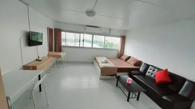 a living room with a couch and a tv in it at CT Impact in Thung Si Kan