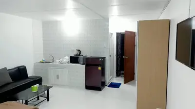 a living room with a couch and a kitchen at CT Impact in Thung Si Kan