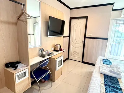 a room with a bed and a desk and a tv at THE BRETON Hotel in Ban O Pao