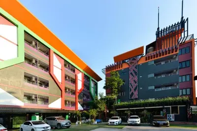 a group of buildings with cars parked in a parking lot at THE BRETON Hotel in Ban O Pao