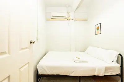 a small bedroom with a bed with white sheets at BAO The Giant Swing - เบา ศาลเจ้าพ่อเสือ ถนนตะนาว in Bangkok