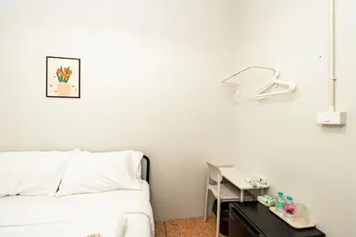 a white room with a bed and a table with a lamp at BAO The Giant Swing - เบา ศาลเจ้าพ่อเสือ ถนนตะนาว in Bangkok
