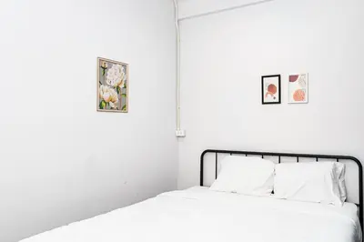 a bed with white sheets and two pictures on the wall at BAO The Giant Swing - เบา ศาลเจ้าพ่อเสือ ถนนตะนาว in Bangkok