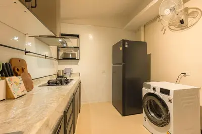 a kitchen with a washing machine and a refrigerator at Oasis Thai Teak Home in Sathorn in Yan Nawa