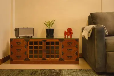 a living room with a couch and a television on a cabinet at Oasis Thai Teak Home in Sathorn in Yan Nawa